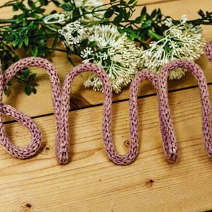 May include: The word "Amy" spelled out in pink knitted yarn.