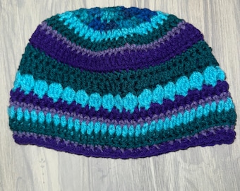 May include: A crocheted hat with a striped pattern in shades of teal, purple, and green.