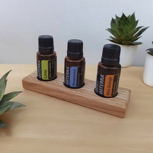 May include: Three brown glass bottles with black caps and labels containing essential oils. The bottles are labelled "dōTERRA Lime", "dōTERRA Peppermint", and "dōTERRA Wild Orange". The bottles are sitting on a wooden stand.