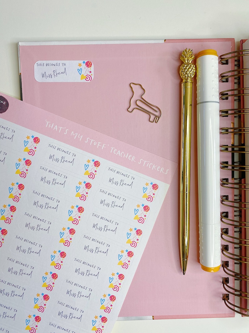 May include: A sheet of colourful teacher stickers with the text "That's My Stuff Teacher Stickers" and "This belongs to Miss Rhead" repeated on each sticker. The stickers feature a variety of colourful shapes and designs, including hearts, stars, and swirls.