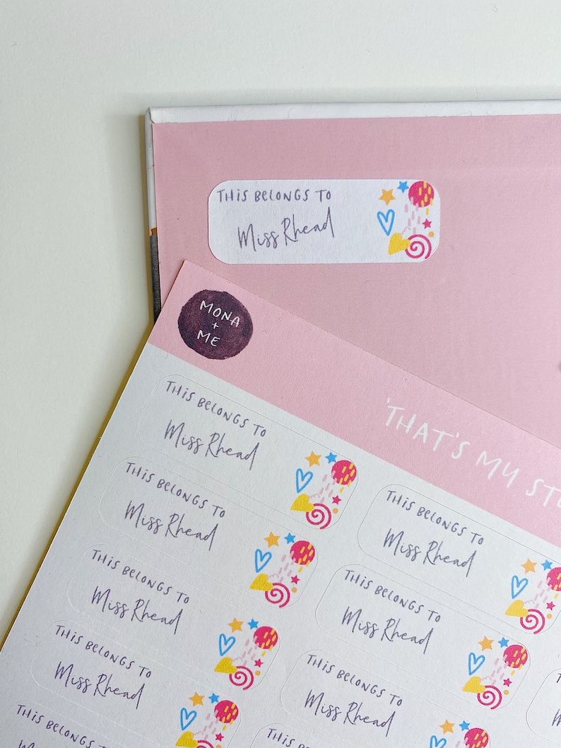 May include: A sheet of colourful, personalised name labels with the text "This belongs to Miss Rhead" and a whimsical design featuring stars, hearts, and swirls.