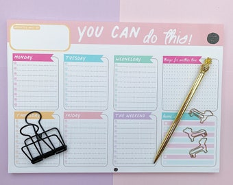 May include: A weekly planner with a pink, yellow, blue, and green color scheme. The planner has sections for each day of the week, including Monday, Tuesday, Wednesday, Thursday, Friday, and the weekend. The planner also has a section for things to do for another time. The planner has a gold pen and a black binder clip on it.
