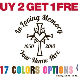 May include: A black decal with the text "In Loving Memory" surrounding a cross with a heart and the years 1950-2010. The decal also includes the text "Your Name Here" and "17 COLORS OPTIONS". The words "BUY 2 GET 1 FREE" are at the top.