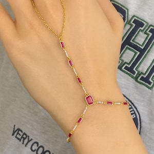 Pulseira delicada de dedo na cor rubi, banhada a ouro 14k e prata 925.