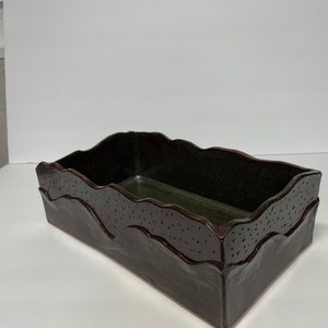 May include: A dark brown ceramic rectangular planter with a wavy rim and a speckled glaze.