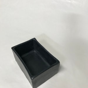 May include: A black rectangular ceramic planter with a smooth, slightly curved surface.