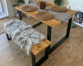 May include: A rustic wooden dining table with black metal legs and a faux fur bench. The table is set with woven placemats and a grey and white patterned tablecloth.