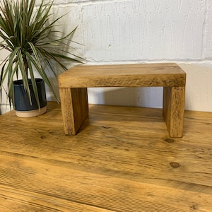 Puede incluir: Un taburete de madera r&uacute;stico con un acabado natural. El taburete est&aacute; hecho de madera reciclada y tiene un dise&ntilde;o simple y minimalista.