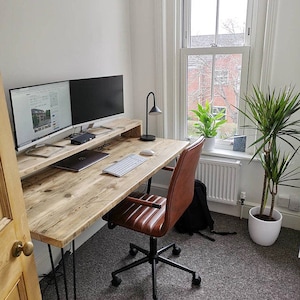 May include: A rustic wooden desk with a black metal frame and two computer monitors. A brown leather office chair with black wheels sits in front of the desk. A potted plant is in the corner of the room.