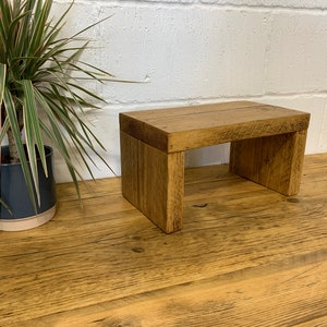 May include: A rustic wooden riser with a natural wood finish. The riser is made of reclaimed wood and has a simple, minimalist design.