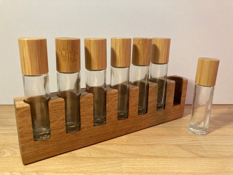 May include: A wooden stand with seven slots for holding small glass bottles with bamboo lids. The stand is made of light brown wood and the bottles are clear glass.