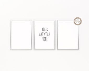 May include: Three white picture frames with silver trim, hanging on a white wall. The center frame has the text "YOUR ARTWORK HERE" printed inside.