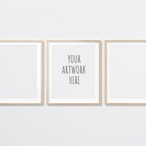 Peut inclure: Trois cadres photo en bois avec des passe-partout blancs, accrochés à un mur blanc. Le cadre du milieu porte le texte "YOUR ARTWORK HERE" imprimé à l'intérieur.