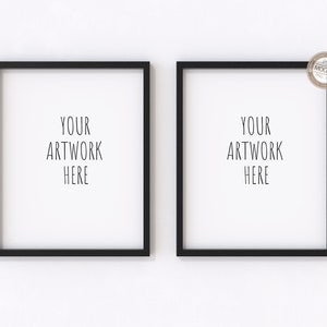 Puede incluir: Dos marcos de fotos negros con paspartús blancos colgados en una pared blanca. Los marcos están vacíos y tienen el texto "YOUR ARTWORK HERE" en cada marco.