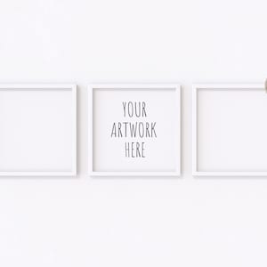 May include: Three white picture frames on a white wall. The centre frame has the text "YOUR ARTWORK HERE" inside.