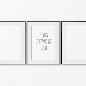 May include: Three black framed pictures hanging on a white wall. The middle picture has the text "YOUR ARTWORK HERE" in black.