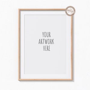 Op de afbeelding: Een licht houten frame met een witte passe-partout en een witte achtergrond. De tekst "YOUR ARTWORK HERE" is in zwart op de witte achtergrond gedrukt.