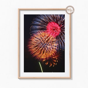 May include: A framed photograph of a colorful fireworks display against a dark night sky. The fireworks are red, orange, yellow, and blue.