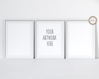 May include: Three white picture frames with a white mat, hanging on a white wall. The center frame has the text "YOUR ARTWORK HERE" printed inside.
