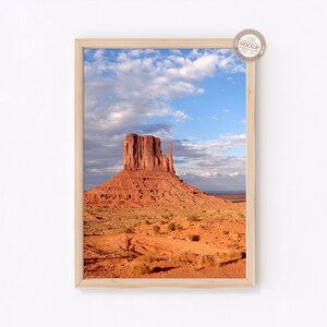 May include: A framed photograph of a red rock formation in a desert landscape. The sky is blue with white clouds.