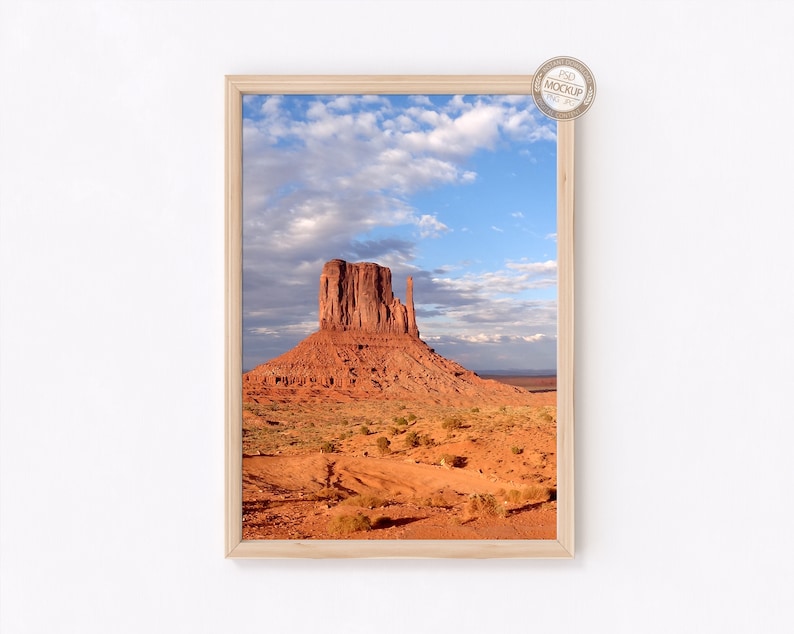 May include: A framed photograph of a red rock formation in a desert landscape. The sky is blue with white clouds.