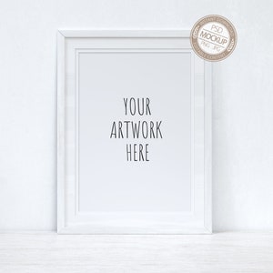 Puede incluir: Maqueta de marco de imagen blanco sobre fondo blanco. El marco está sobre una superficie blanca. El texto "YOUR ARTWORK HERE" está escrito en negro dentro del marco.