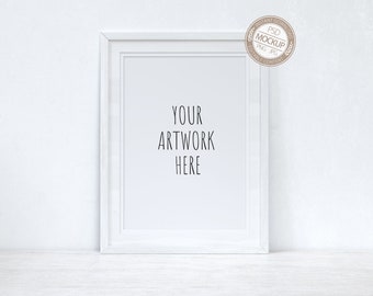 May include: White picture frame mockup with a white background. The frame is on a white surface. The text "YOUR ARTWORK HERE" is written in black inside the frame.