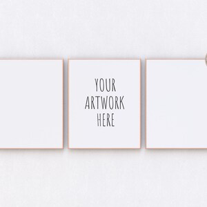 Peut inclure: Trois images encadrées blanches sur un mur blanc. L'image du milieu porte le texte "YOUR ARTWORK HERE" en noir.