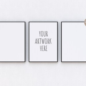 May include: Three black framed canvases hanging on a white wall. The center canvas has the text "YOUR ARTWORK HERE" printed on it.