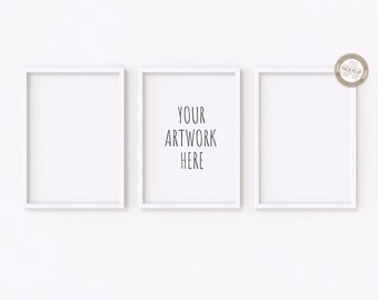 May include: Three white picture frames on a white wall. The middle frame has the text "YOUR ARTWORK HERE" inside.
