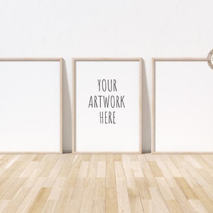 Könnte beinhalten: Drei Holzrahmen mit weißen Passepartouts und weißen Hintergründen. Der mittlere Rahmen trägt den Text "YOUR ARTWORK HERE" in Schwarz.