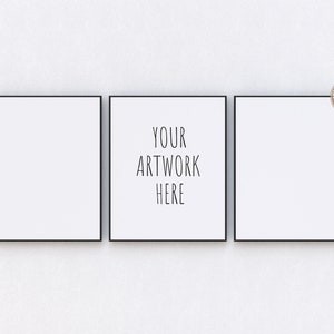 Peut inclure: Trois toiles encadrées noires sur un mur blanc. La toile du centre porte le texte "YOUR ARTWORK HERE" en noir.