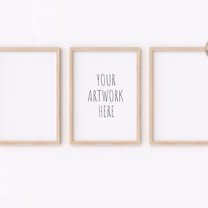 Op de afbeelding: Drie houten fotolijsten met witte passe-partouts, hangend aan een witte muur. De middelste lijst heeft de tekst "YOUR ARTWORK HERE" in zwart.
