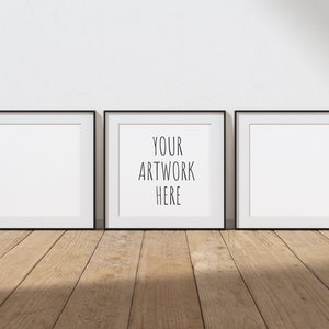 May include: Three black picture frames with white mats hanging on a white wall. The center frame has the text "YOUR ARTWORK HERE" printed inside.