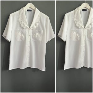 Vintage Sekretärinnenbluse aus den 1980er Jahren, weiß, aus Polyester, kurzärmelig, mit Seitenschlitzen und aufgesetzten Taschen, Größe M-L