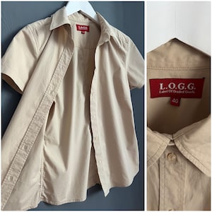 Könnte beinhalten: Ein beigefarbenes Hemd mit kurzen Ärmeln und Knöpfen mit einem roten Etikett, auf dem "L.O.G.G. Label of Graded Goods 40" steht.