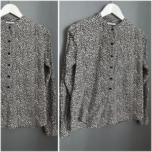 May include: A black and white patterned long-sleeved shirt with a mandarin collar and button fastening.