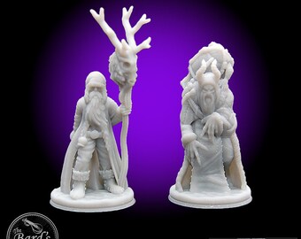 May include: Two 3D printed miniature figures of wizards, one with a staff topped with a skull and antlers, the other with a staff topped with a skull and horns. Both figures are wearing robes and have long beards. The figures are printed in a light gray color. The figures are from Hero's Hoard, a company that makes 3D printed miniatures.
