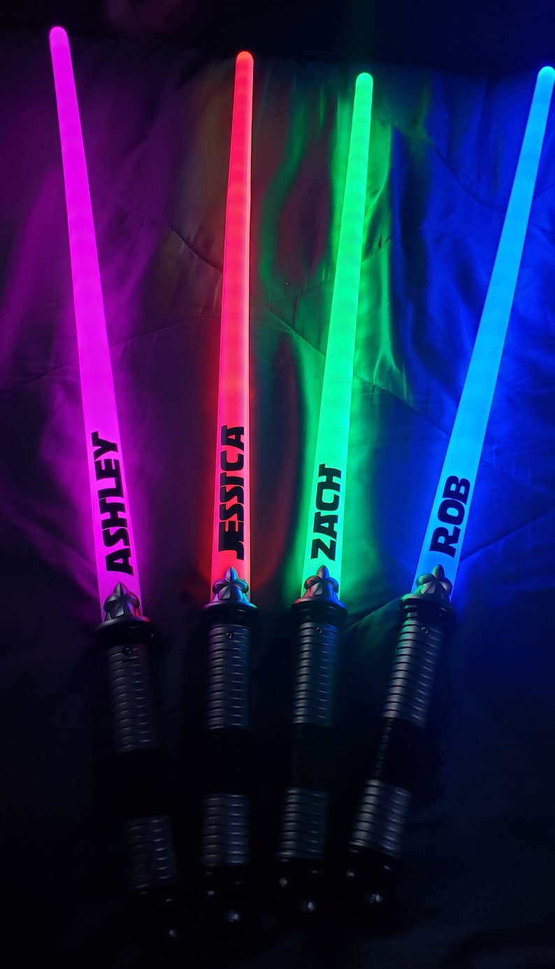 Peut inclure: Quatre &eacute;p&eacute;es lumineuses color&eacute;es avec des poign&eacute;es noires et les noms "Ashley", "Jessica", "Zach" et "Rob" &eacute;crits dessus.