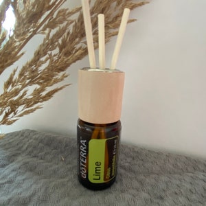 Könnte beinhalten: Eine braune Glasflasche mit ätherischem Öl und einem hellgrünen Etikett mit der Aufschrift "Lime" und "Citrus". Die Flasche hat einen Holzdeckel mit drei Holzstäbchen zur Diffusion. Der Markenname "doTERRA" ist aufgedruckt.