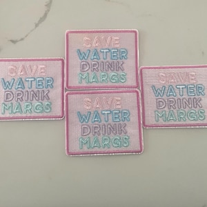 May include: Four pink embroidered patches with the text "Save Water Drink Margs" in different colored lettering.