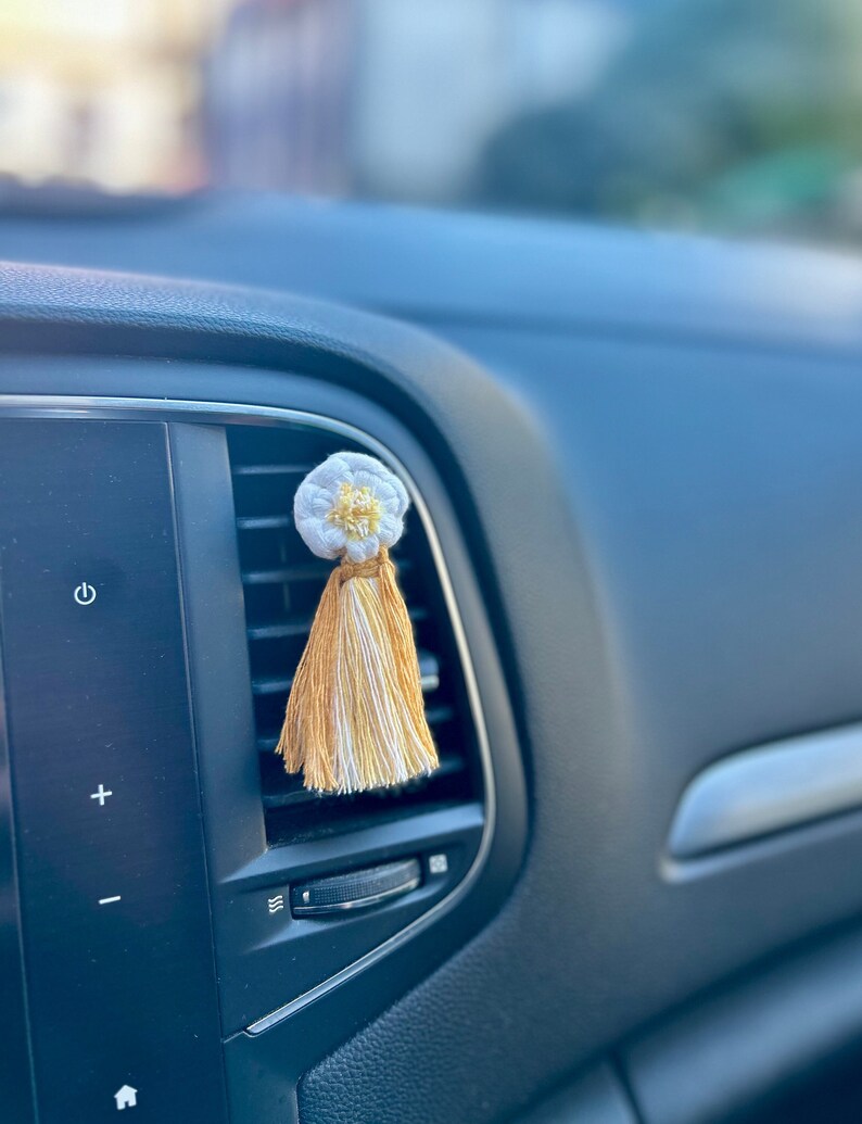 Diffuseur à clip pour voiture en macramé pour diffuser les huiles essentielles et parfumer l'habitacle de la voiture. Macramé en forme de marguerite accroché à un clip pour ventilation de voiture