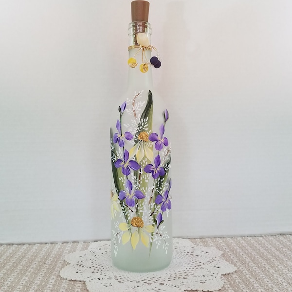 Frosted wine bottle.  Hand painted.  Purple, yellow and white garden flowers.  Lights up.
