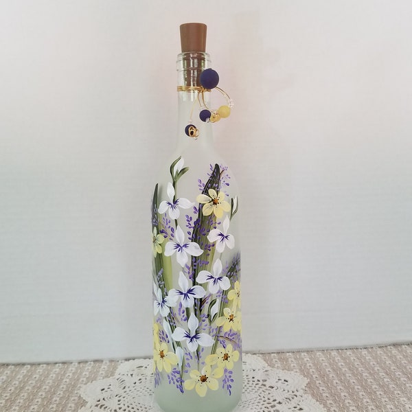 Frosted wine bottle.  Hand painted.  White, yellow and purple garden flowers.  Lights up.