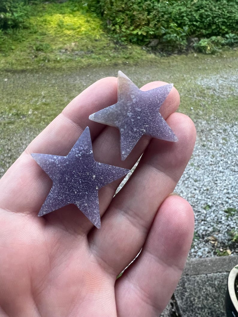 May include: Two purple star-shaped crystals with a sparkly finish.