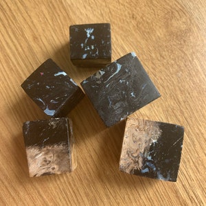 May include: Five small, dark brown, cube-shaped pieces of polished stone with white and light brown marbling.