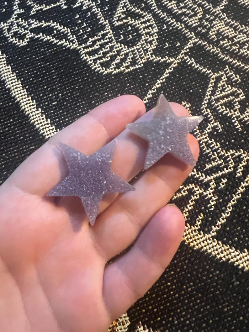 May include: Two purple glitter star-shaped resin earrings.