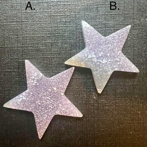 May include: Two iridescent purple glitter star-shaped ornaments with a textured surface. The stars are labeled "A." and "B."