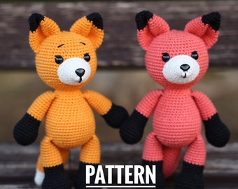 May include: Two handmade crochet fox dolls, one orange and one pink, stand side-by-side. They have black paws and ear tips, white faces, and black eyes. The text "PATTERN PDF ONLY" is at the bottom.