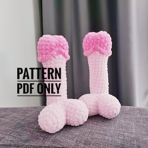 Könnte beinhalten: Zwei handgefertigte, hellrosa gehäkelte Objekte in Phallusform mit einem dunkleren rosa Kopf. Der Text "PATTERN PDF ONLY" ist in schwarzer Schrift auf dem Bild überlagert. Die Objekte werden auf einer grauen Oberfläche dargestellt.